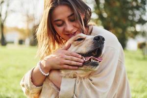 abrazando a la mascota. mujer joven tiene un paseo con golden retriever en el parque foto