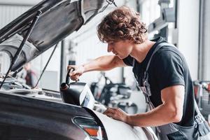 cambio de aceite hombre adulto con uniforme de color gris trabaja en el salón del automóvil foto