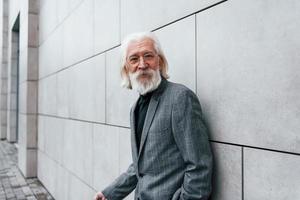 hombre de negocios senior en ropa formal, con pelo gris y barba está al aire libre foto