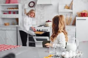 producto terminado. abuela mayor con su nieta cocina dulces para navidad en la cocina foto