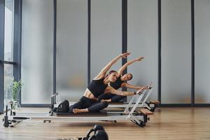 usando equipo de gimnasio. dos mujeres con ropa deportiva y cuerpos delgados tienen un día de yoga fitness juntas en el interior foto