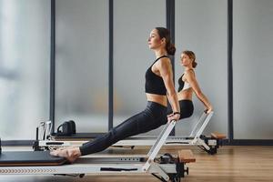 fuerza de las manos. dos mujeres con ropa deportiva y con cuerpos delgados tienen un día de yoga en el interior juntas foto