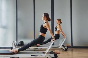 fuerza de las manos. dos mujeres con ropa deportiva y con cuerpos delgados tienen un día de yoga en el interior juntas foto