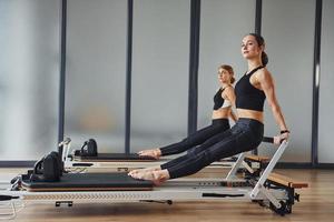 fuerza de las manos. dos mujeres con ropa deportiva y con cuerpos delgados tienen un día de yoga en el interior juntas foto