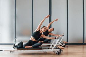 usando equipo de gimnasio. dos mujeres con ropa deportiva y cuerpos delgados tienen un día de yoga fitness juntas en el interior foto