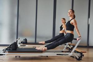 fuerza de las manos. dos mujeres con ropa deportiva y con cuerpos delgados tienen un día de yoga en el interior juntas foto