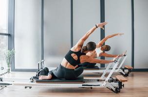 usando equipo de gimnasio. dos mujeres con ropa deportiva y cuerpos delgados tienen un día de yoga fitness juntas en el interior foto