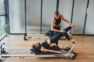 aprende nuevos ejercicios. dos mujeres con ropa deportiva y cuerpos delgados tienen un día de yoga fitness juntas en el interior foto