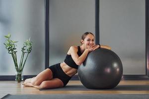 tomando un descanso. mujer joven en ropa deportiva y con cuerpo delgado tiene un día de yoga fitness en el interior foto