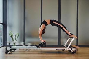 mujer joven en ropa deportiva y con cuerpo delgado tiene un día de yoga fitness en el interior foto