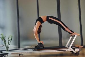 mujer joven en ropa deportiva y con cuerpo delgado tiene un día de yoga fitness en el interior foto