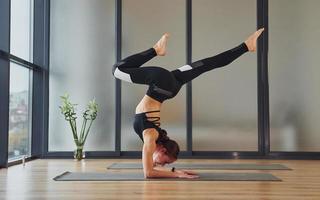 Concentrated on exercise. Young woman in sportive wear and with slim body have fitness yoga day indoors photo