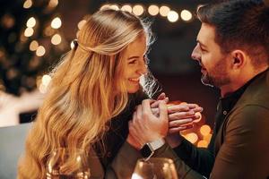 Side view. Young lovely couple have romantic dinner indoors together photo