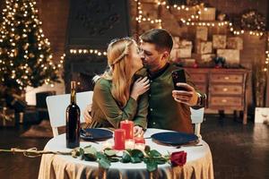 haciendo selfie usando el teléfono. joven pareja encantadora tiene una cena romántica en el interior juntos foto