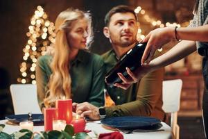 Waiter waits for payment. Young lovely couple have romantic dinner indoors together photo