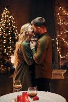 Standing in the Christmas decorated room. Young lovely couple have romantic dinner indoors together photo