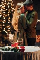 Standing in the Christmas decorated room. Young lovely couple have romantic dinner indoors together photo