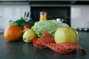 vista de cerca de la comida vegetariana que está sobre la mesa en la cocina. cinta métrica, manzanas, naranja, jugo foto