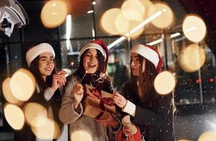 With Bengal lights. Three cheerful women spends Christmas holidays together outdoors. Conception of new year photo