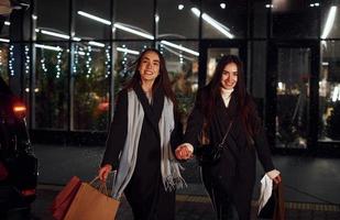 paseos con paquetes. solo de compras. hermanas gemelas felices pasan las vacaciones de navidad juntas al aire libre. concepción de año nuevo foto