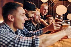 Fans cheer and shout. Group of people together indoors in the pub have fun at weekend time photo