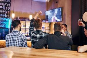 Football fans watching TV. Group of people together indoors in the pub have fun at weekend time photo