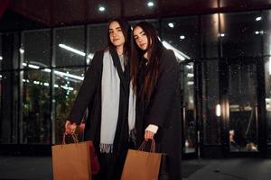 paseos con paquetes. solo de compras. hermanas gemelas felices pasan las vacaciones de navidad juntas al aire libre. concepción de año nuevo foto