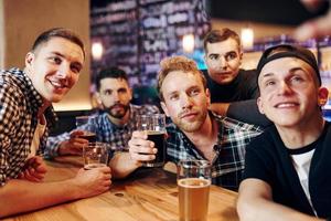 Man takes selfie by phone. Group of people together indoors in the pub have fun at weekend time photo
