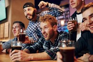 Soccer fans celebrating victory. Group of people together indoors in the pub have fun at weekend time photo