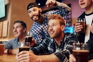 Soccer fans celebrating victory. Group of people together indoors in the pub have fun at weekend time photo