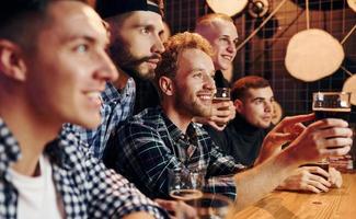 Fans cheer and shout. Group of people together indoors in the pub have fun at weekend time photo