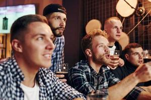 Fans cheer and shout. Group of people together indoors in the pub have fun at weekend time photo