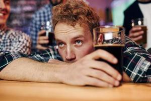 Sad man feels bad. Group of people together indoors in the pub have fun at weekend time photo