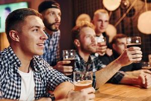 Fans cheer and shout. Group of people together indoors in the pub have fun at weekend time photo