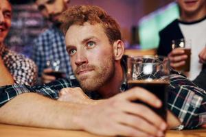 Sad man feels bad. Group of people together indoors in the pub have fun at weekend time photo