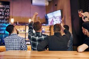 Football fans watching TV. Group of people together indoors in the pub have fun at weekend time photo