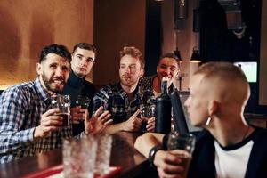 Expressive people watching soccer. Group of people together indoors in the pub have fun at weekend time photo