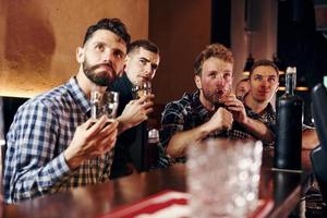 Expressive people watching soccer. Group of people together indoors in the pub have fun at weekend time photo