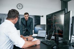 Conception of teamwork. Team of stockbrokers works in modern office with many display screens photo