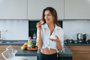 taza con bebida y galleta. joven europea está en el interior de la cocina con comida saludable foto