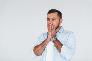 Feels shocked. Young handsome man standing indoors against white background photo