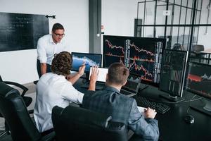 Conception of teamwork. Team of stockbrokers works in modern office with many display screens photo