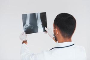 Medic with x-ray. Young handsome man standing indoors against white background photo