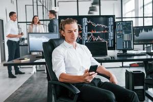 Ordinary office day. Team of stockbrokers works in indoors with many display screens photo