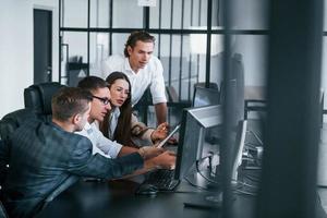 Analysing information. Team of stockbrokers works in modern office with many display screens photo