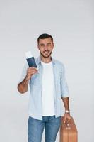 Tourist with ticket. Young handsome man standing indoors against white background photo