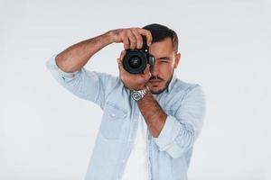 With professional camera. Young handsome man standing indoors against white background photo