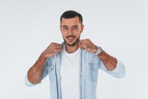 Fashionable young man standing indoors against white background photo