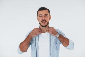 Fashionable young man standing indoors against white background photo