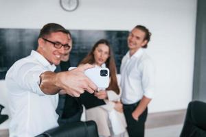 Making selfie. Group of young smart people that standing near blackboard in office photo